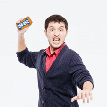 a man in a blue cardigan is holding up a can of ign-bru