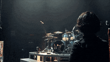 a man stands in front of a drum set that has a skull on it