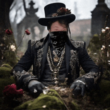 a man wearing a top hat and a bandana sitting in the dirt