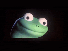 a green frog with big white eyes is looking at the camera in a dark room .