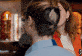a woman in a blue shirt is kissing another woman on the cheek