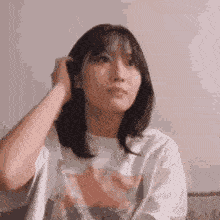a woman is sitting on a couch holding her hair and looking at the camera .