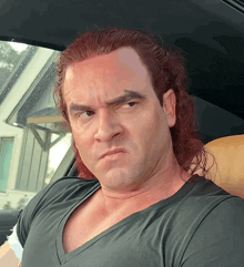 a man with red hair is sitting in a car looking at the camera