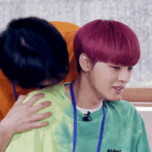 a man with pink hair is hugging another man