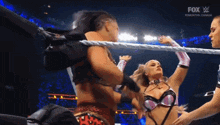 two women are wrestling in a ring with a fox broadcast in the background