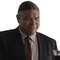a man in a suit and tie smiles while holding a glass of wine