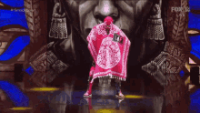 a man in a red poncho is standing in front of a fox live broadcast