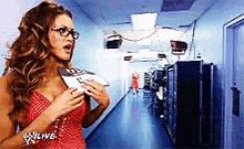 a woman in a red dress is standing in a hallway with a sign that says w live on it