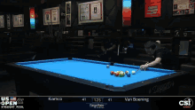 a pool table with a blue cloth and a man holding a cue