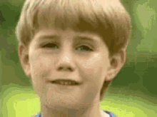 a young boy with blonde hair is smiling and looking at the camera