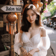 a woman in a white dress stands in front of a sign for balon 168