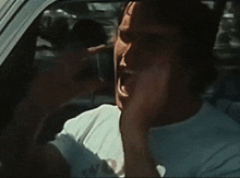 a man in a white shirt is driving a car