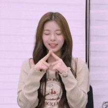 a young woman is making a peace sign with her hands while wearing a sweater .