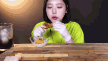 a woman wearing gloves is eating a piece of food