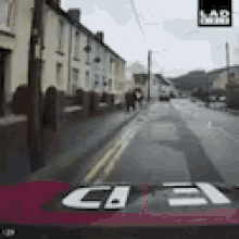 a red car is driving down a street with the number 3 on the back window