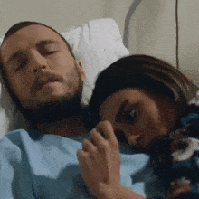 a man and a woman are laying in a hospital bed with their eyes closed