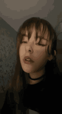a close up of a woman 's face with her eyes closed and a choker around her neck