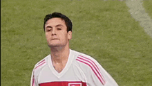a soccer player wearing a white and red jersey with a turkish flag on it is running on the field .