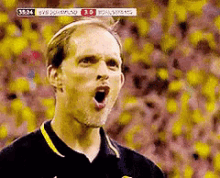 a soccer player is screaming in front of a crowd with a score of 3 to 0