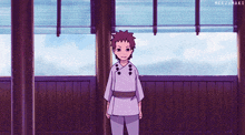 a young boy in a purple shirt and pants is standing in front of a window ..