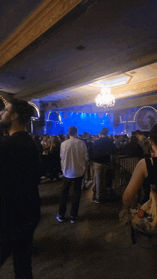 a crowd of people standing in front of a stage with a blue light on it