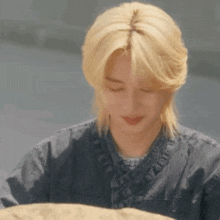 a young man with blonde hair is sitting down with his eyes closed and looking down .