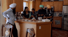 a group of people standing around a kitchen counter with plates of food on it