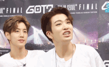 two young men are standing next to each other in front of a sign that says got7