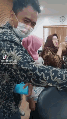 a man wearing a mask is standing in front of a group of people with tiktok written on the bottom right