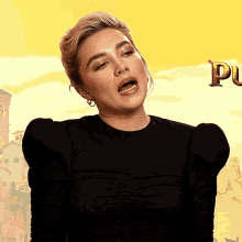 a woman with a nose ring is standing in front of a yellow background with the letter p on it