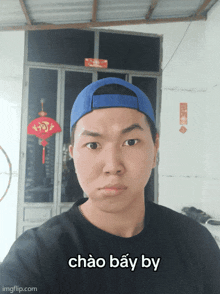 a man wearing a blue hat and a black shirt has the words chao bay by written on his face