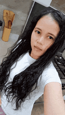 a woman with long black hair is taking a selfie in front of a stove