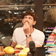 a man in a white shirt is sitting at a table eating a sandwich .