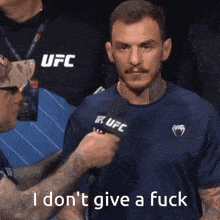 a man speaking into a microphone with the words " i don 't give a fuck " on the bottom
