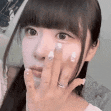 a close up of a girl covering her face with her hand .