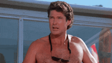 a shirtless man wearing sunglasses and a necklace around his neck