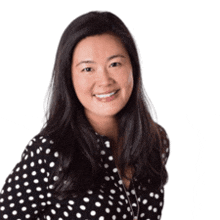 a woman in a black and white polka dot shirt is smiling