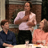 a man in a pink shirt is talking to a woman