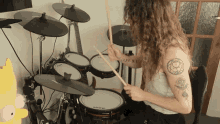 a woman with a tattoo on her arm playing a drum set