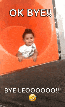 a little girl is sitting on an orange slide with the words ok bye bye leo written on the bottom .