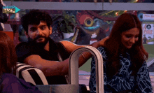 a man and a woman are sitting in front of a sign that says 24hr live