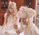 two dolls are sitting at a table and one is wearing a crown