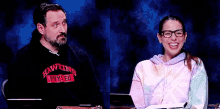 a man and a woman are sitting at a table with a blue background .