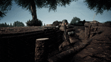 a man in a helmet sits in a trench holding a gun