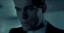a close up of a man 's face in a suit and tie in the dark .