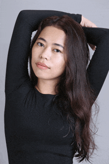 a woman wearing a black shirt with her arms behind her head