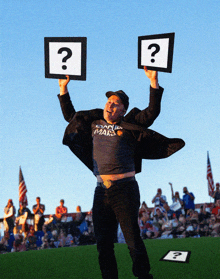 a man in a shirt that says canada mars holds up two signs with question marks on them