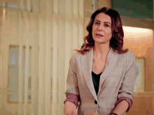 a woman in a plaid jacket stands in a room