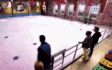 a group of people are standing in front of an ice rink .