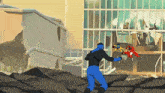 a man in a blue suit is standing in front of a destroyed building holding a gun